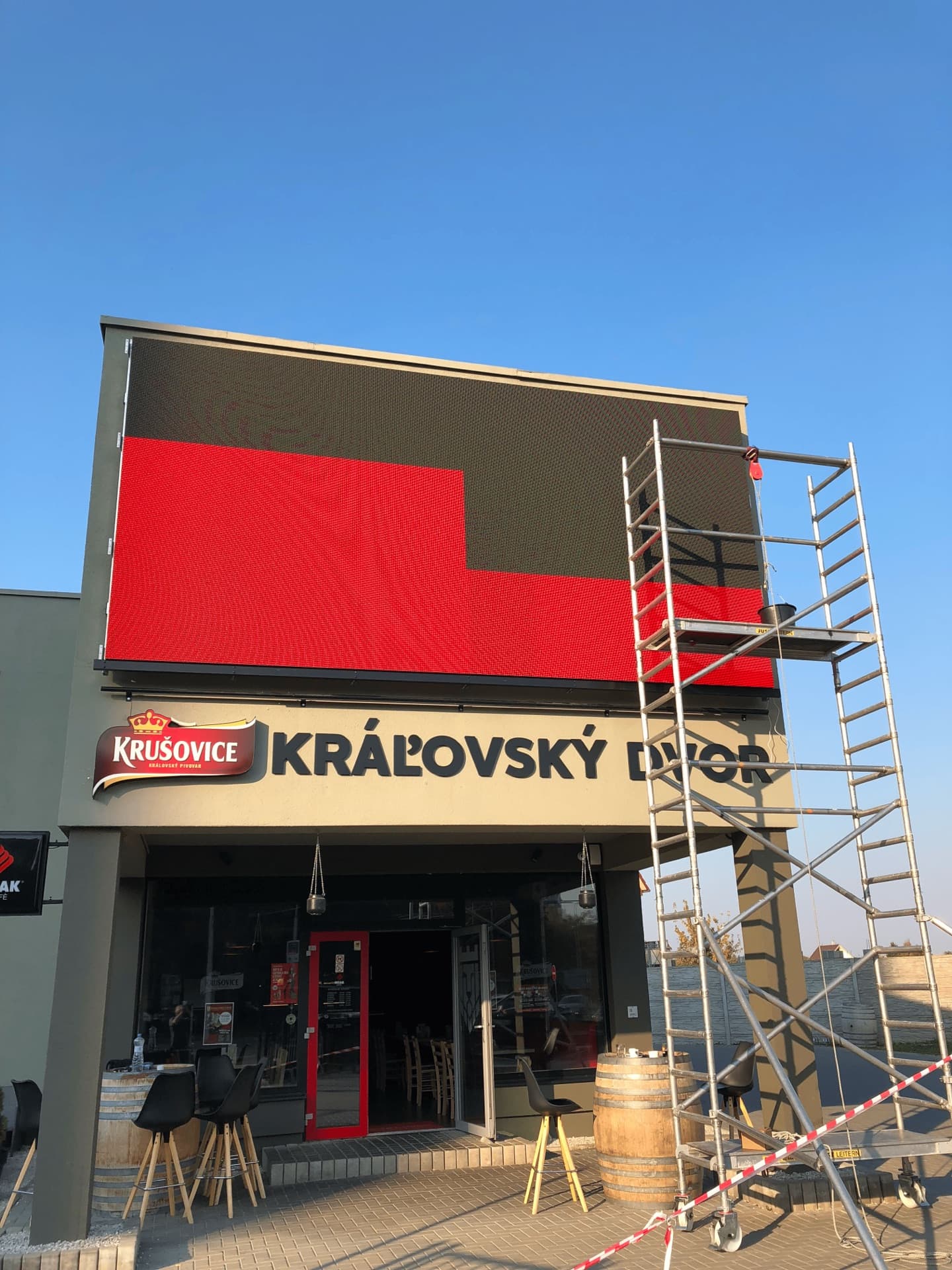 Fasádna LED obrazovka GMITTER MEDIA čitateľná za plného denného svetla nad vstupom do prevádzky